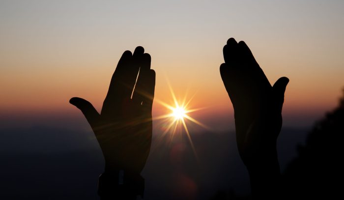 Faith of christian concept: Spiritual prayer hands over sun shin Faith of christian concept: Spiritual prayer hands over sun shine with blurred beautiful sunset background